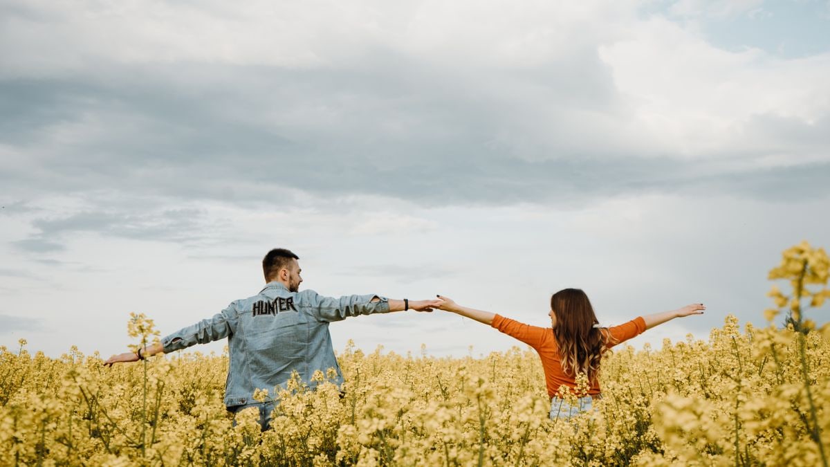 A couple enjoying a warm summer day in a vibrant yellow flower field, radiating joy and freedom.
